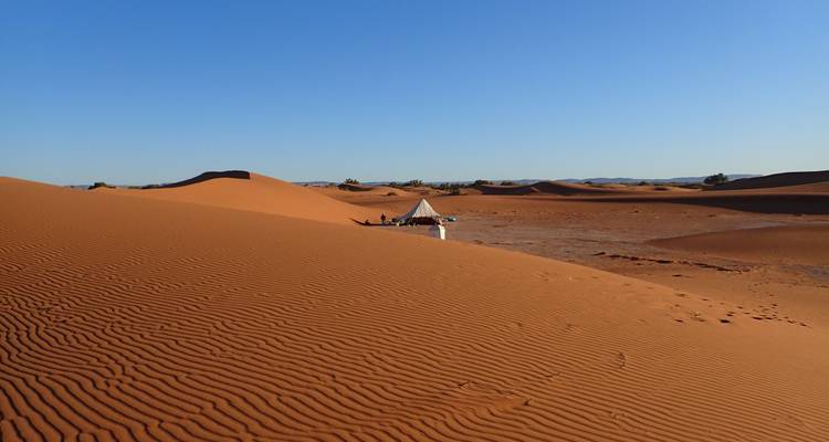 Wüstenlandschaft mit Sanddünen und einem Zelt.