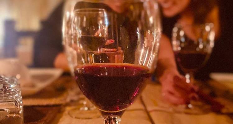 Twee mensen die zitten met wijnglazen op een tafel in een schemering verlichte omgeving.