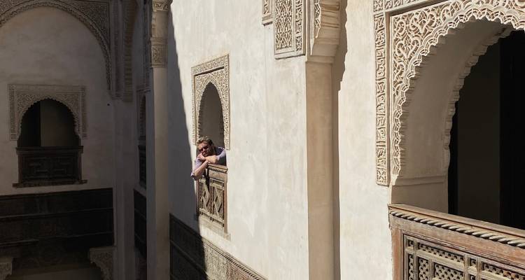 Een persoon die uitkijkt vanaf een balkon met ingewikkeld steenwerk in een historisch gebouw.
