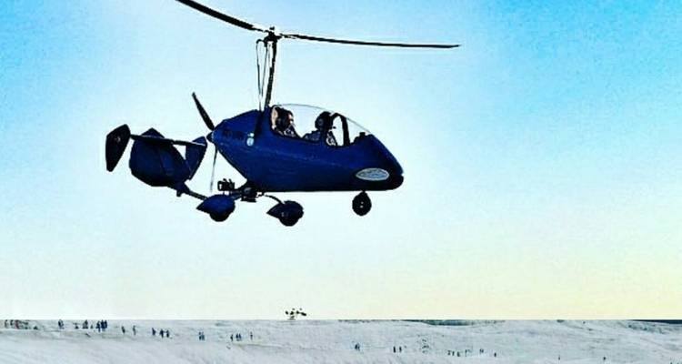 Un pequeño helicóptero volando sobre un paisaje cubierto de nieve.