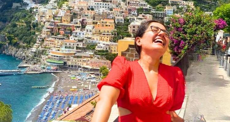 Personne en robe rouge souriant devant le littoral de Positano.