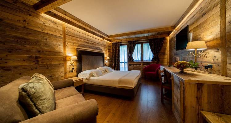 Chambre d'hôtel à thème boisé avec un lit double et une décoration chaleureuse.