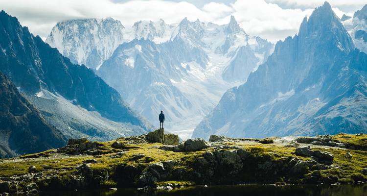Personne debout sur des rochers avec une vue panoramique sur les montagnes.