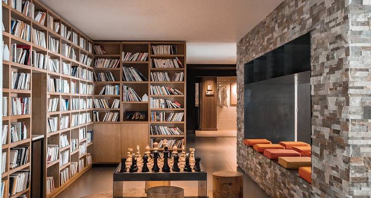 Intérieur de bibliothèque avec des étagères de livres et un jeu d'échecs installé.
