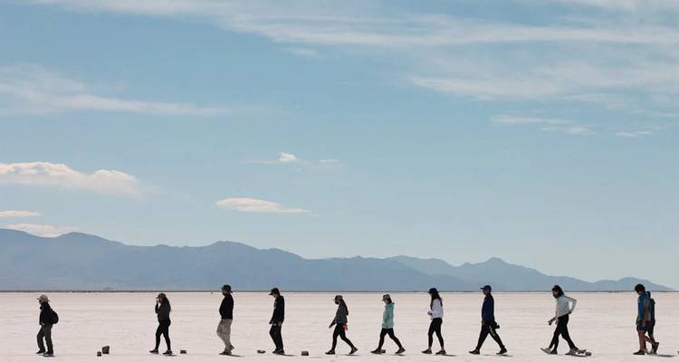 Grupo de personas caminando en un paisaje desértico.