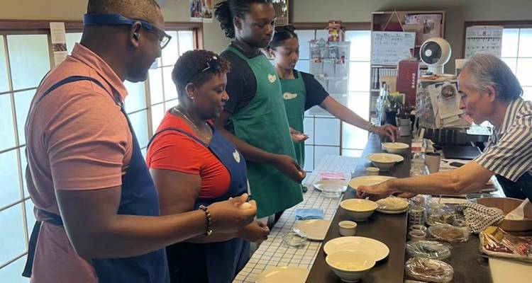 Gruppe von Menschen, die in einer Küche eine Kochaktivität ausüben.
