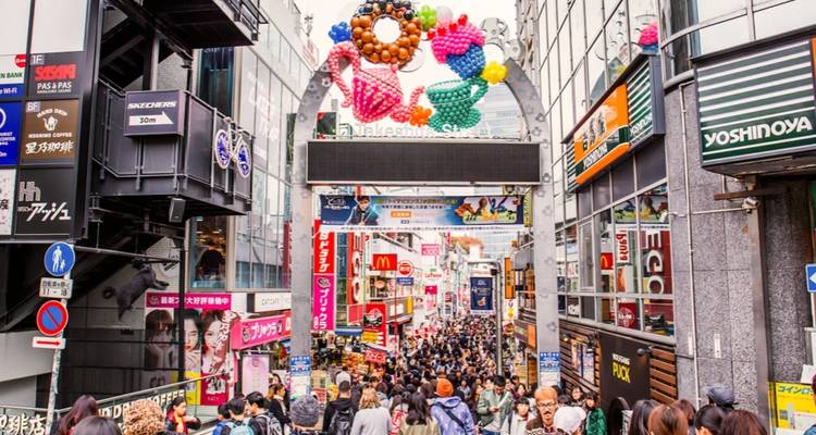 Überfüllte Einkaufsstraße in Tokyo mit bunten Schildern und Luftballons.