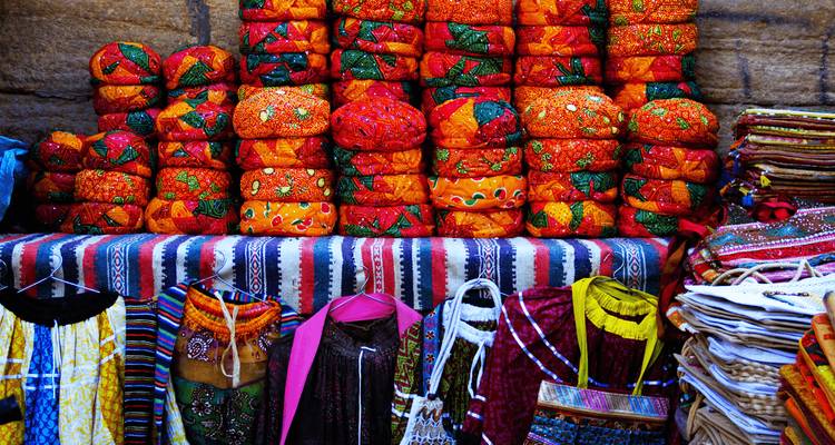 Textiles colorés et turbans exposés sur un marché.