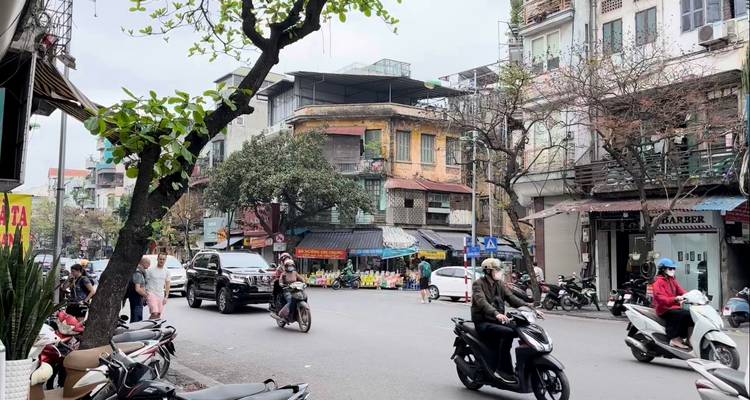 Een drukke Vietnamese straat met motorfietsen, voertuigen en winkels langs de straat.