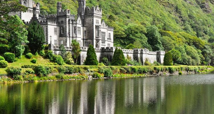 Grande abbaye néo-gothique de Kylemore parfaitement reflétée dans un lac serein du Connemara adossé à des collines verdoyantes.