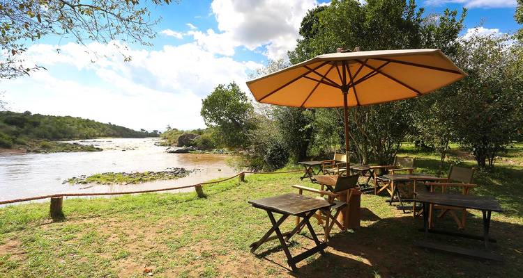 Terrasse extérieure sous un parasol au bord d'une rivière.