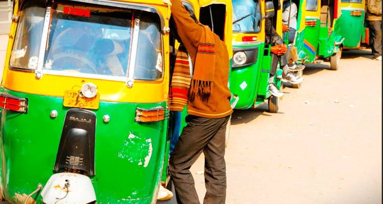 Een rij felgroene auto-riksja's met een persoon die in een van hen instapt.