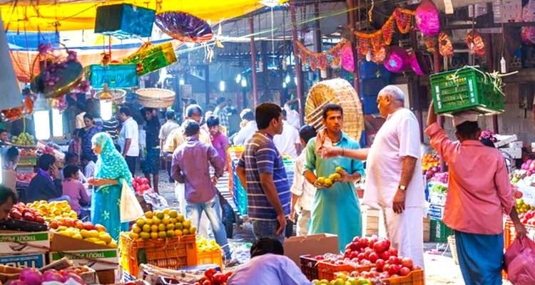 Een drukke marktscène met verschillende vruchten en groepen mensen eromheen.