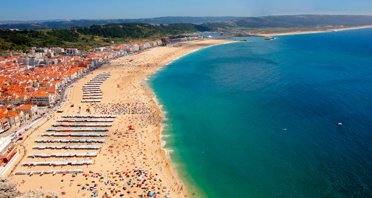 Aerial view of a crowded beach with city in the background.