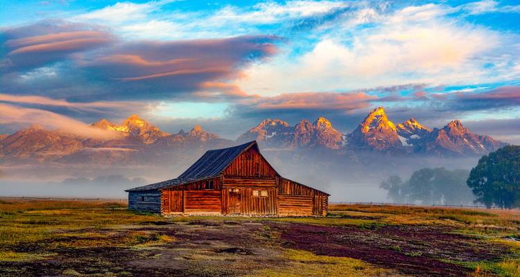 Barn at sunrise with Grand Teton mountains in the background.