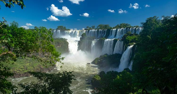 Iguazu-watervallen met weelderig groen en blauwe lucht.