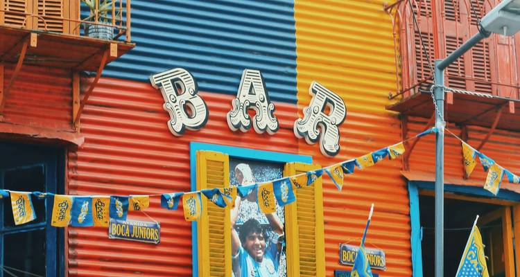 Kleurrijke gevel met het woord 'BAR' en verzamelde mensen.