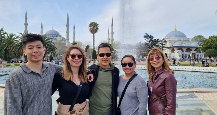 Groupe de personnes posant devant une mosquée historique avec des dômes et des minarets.