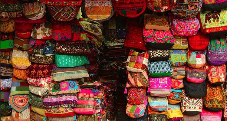 Étalage coloré de textiles traditionnels et de coussins sur un marché.