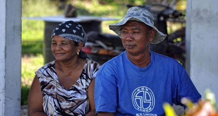 Two people sitting and smiling outdoors.