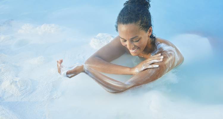 Vrouw geniet van een warmwaterbron met stoom eromheen.