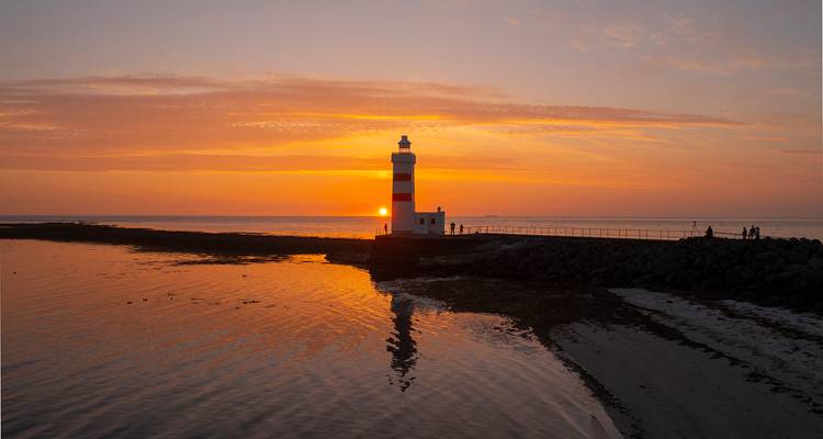 Vuurtoren bij zonsondergang aan de kust.