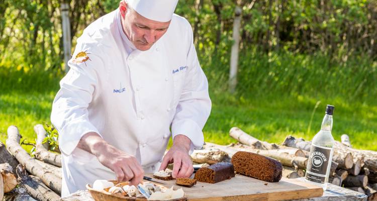 Chef die buiten eten aan het bereiden is met verschillende ingrediënten.