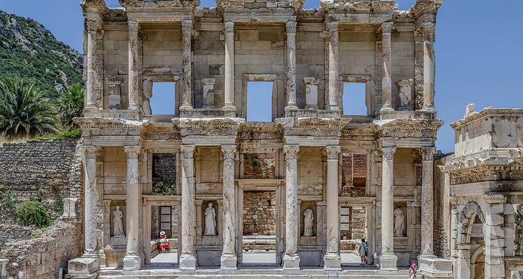 Ruines anciennes d'une bibliothèque avec des statues et des colonnes.