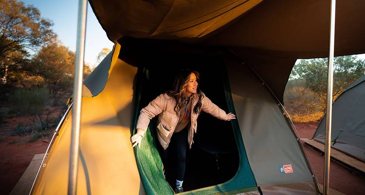 Person emerging from a tent in a desert setting.