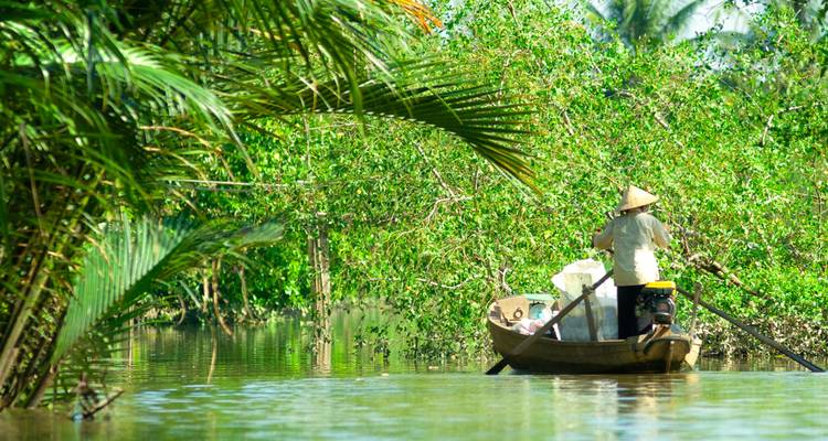 Un navegante solitario rema a través de exuberantes manglares verdes en el Delta del Mekong