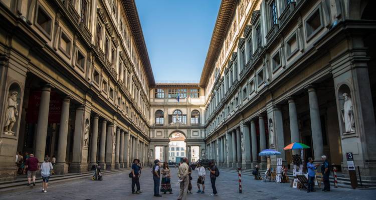 Menschen versammeln sich im großen Hof der Uffizien, der von hohen Säulen flankiert wird.
