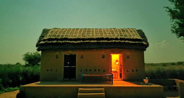 Hutte traditionnelle illuminée dans la nuit d'une lumière chaleureuse.