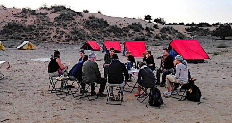 Groupe de personnes assises autour d'une table dans un campement du désert.