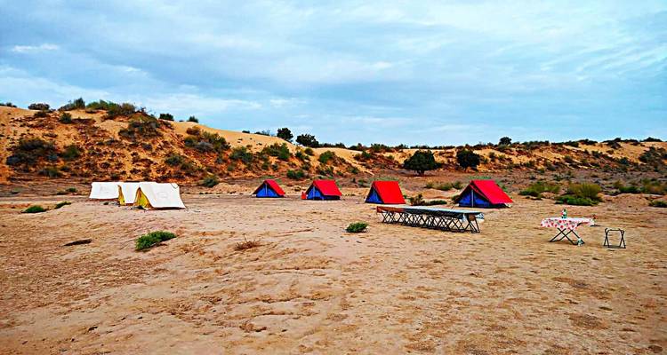 Tentes installées dans un environnement désertique sablonneux.