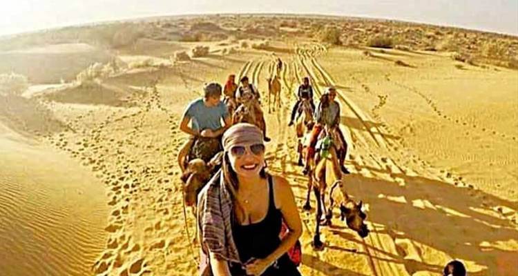 Groupe chevauchant des chameaux à travers le désert.