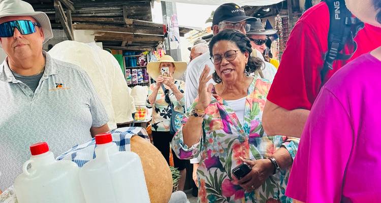 Besucher wandeln durch einen belebten Bereich mit Marktständen im Freien und betrachten lokale Waren.