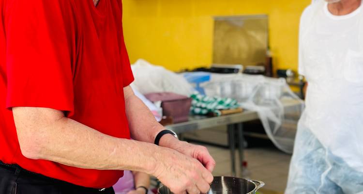 Mann im roten Hemd bereitet Zutaten während eines praktischen ghanaischen Kochworkshops vor.