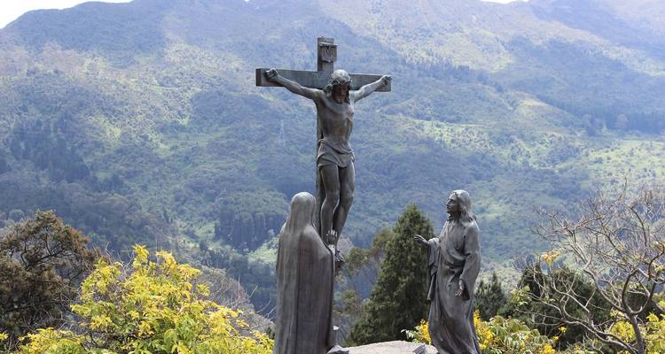 Beelden van religieuze figuren tegen een bergachtig landschap.
