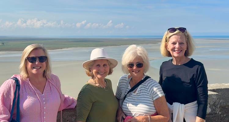 Quatre femmes posant avec un vaste paysage en arrière-plan.