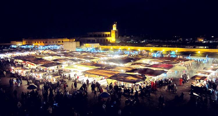 Night market with lit stalls and a crowd of people at night.