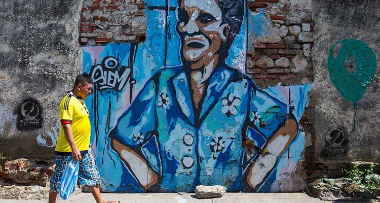 Personne marchant devant une fresque murale dans une rue urbaine.