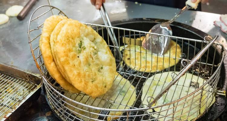 Gros plan de pains plats frits en cours de préparation dans une cuisine.