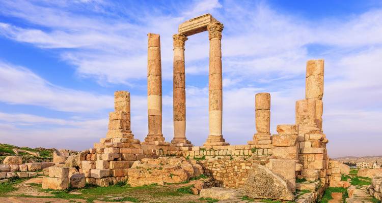 Des colonnes romaines antiques bien conservées s'élèvent vers un ciel vibrant parsemé de légers nuages