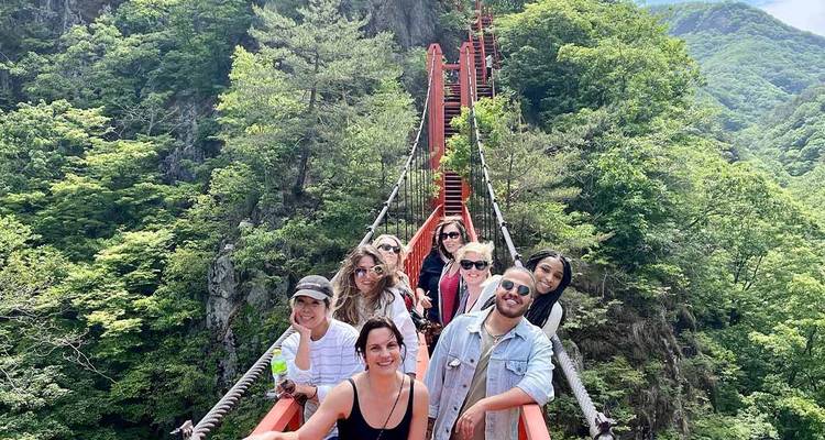 Groupe de personnes posant sur un pont suspendu entouré d'une végétation luxuriante.