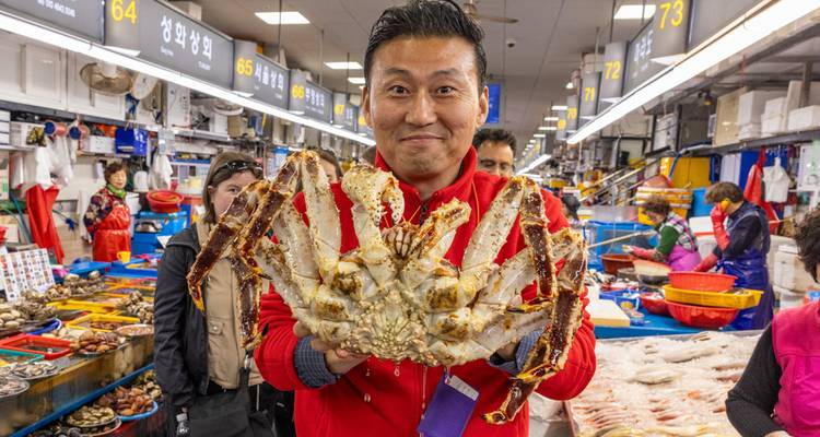 Homme tenant un gros crabe dans un marché aux fruits de mer.