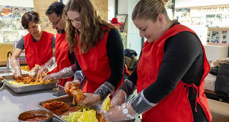 Groupe de personnes préparant du kimchi dans une cuisine.