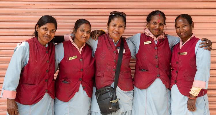 Five women in uniform smiling and posing together.