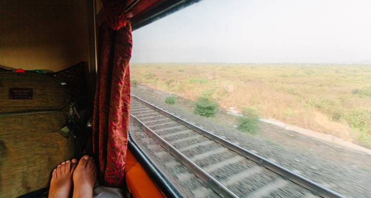 View from a train window overlooking railway tracks and grassy fields.