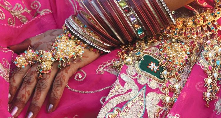 Close-up of traditional jewelry and henna-adorned hands.