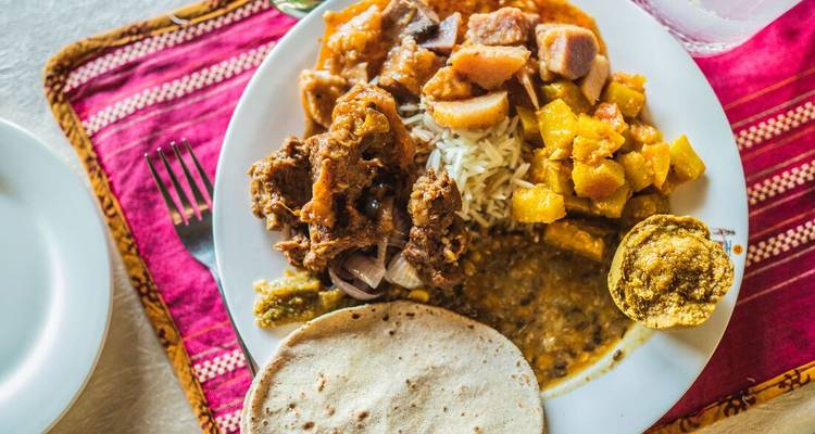 Assiette de cuisine indienne variée sur un set de table coloré.
